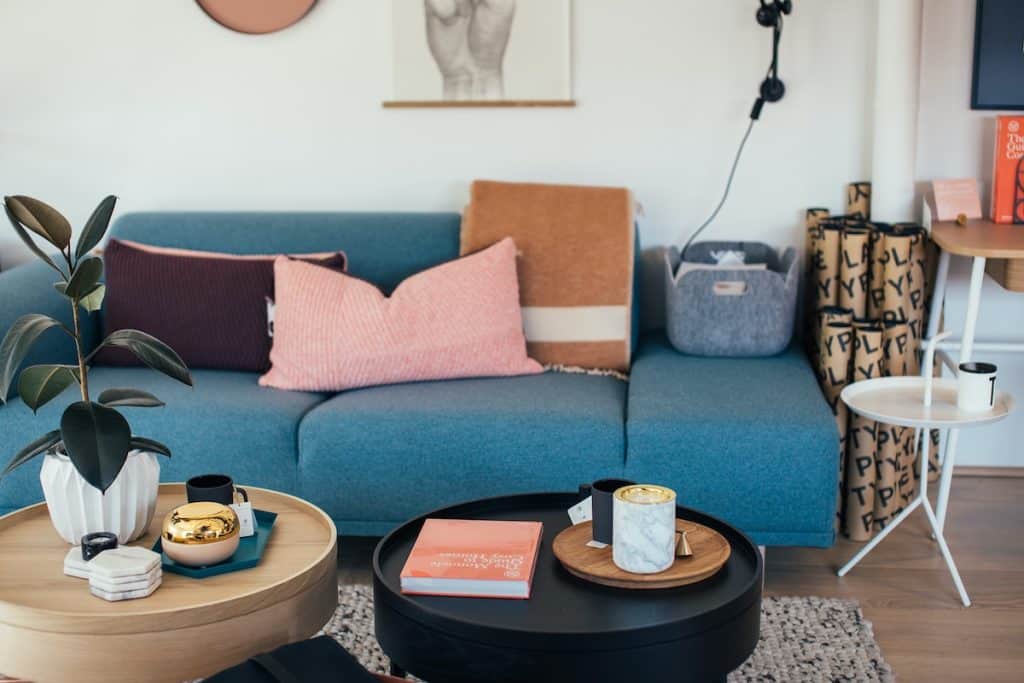 living room with blue couch, scatter pillows, a wooden and black round coffee table