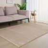sand coloured rug on a wooden floor with soft pink sofa in the backgound