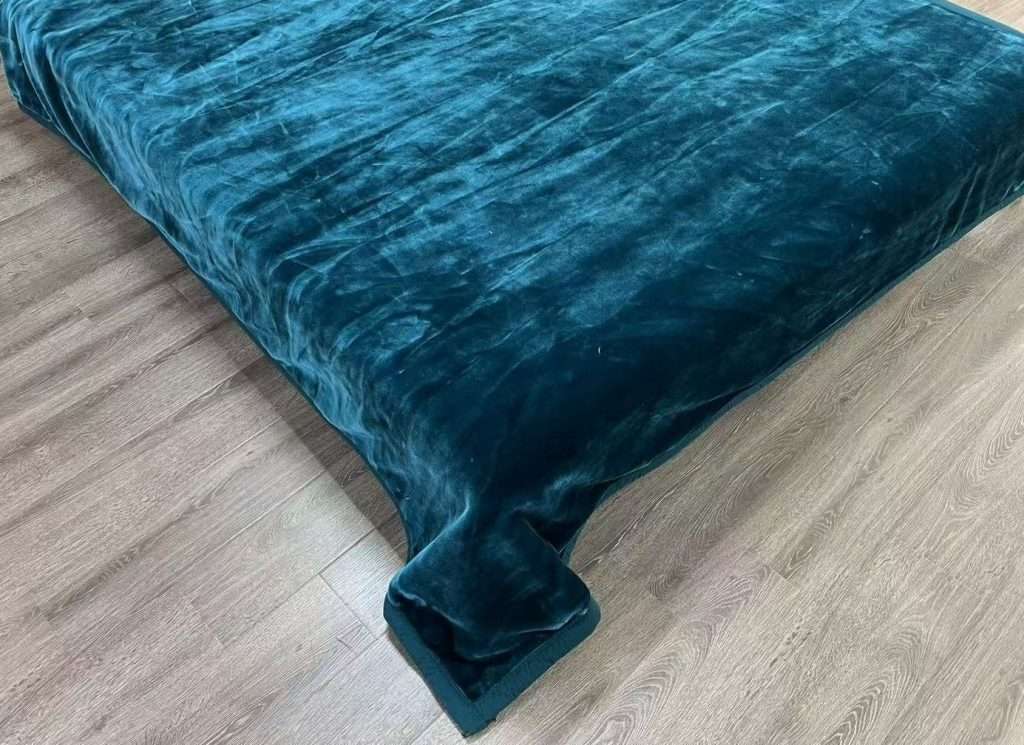 Teal velvet bedspread on wooden floor