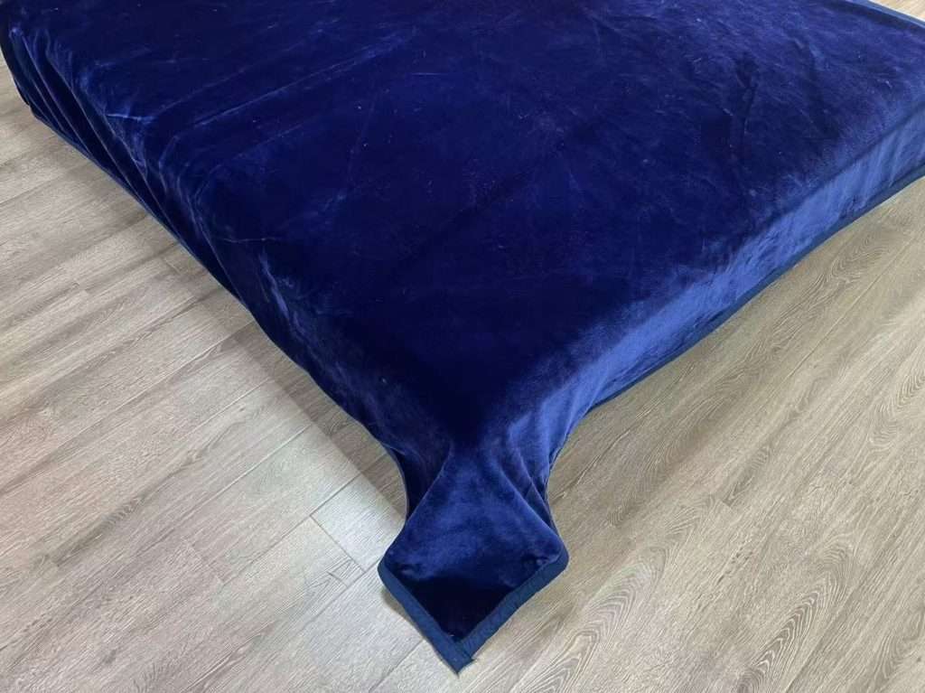 Navy blue velvet bedspread on wooden floor