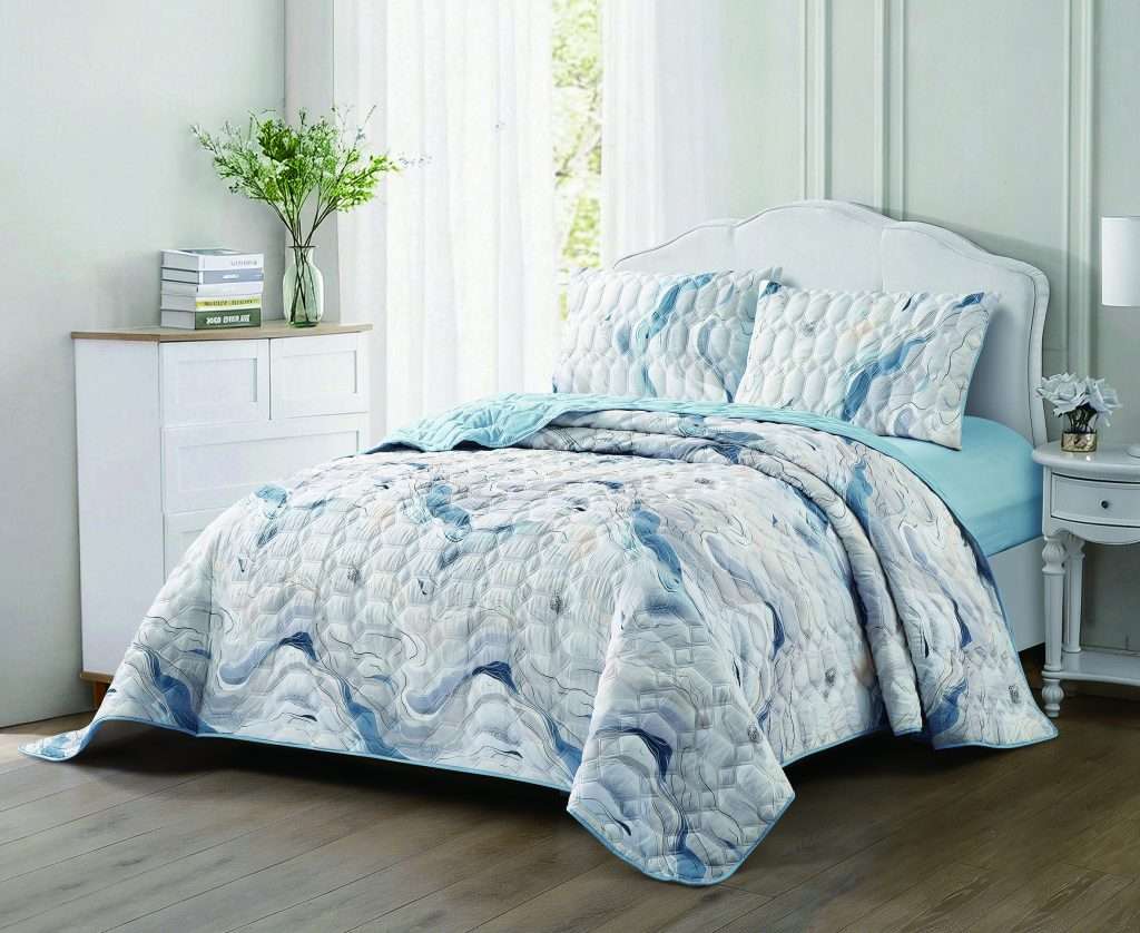 Blue patterned quilt on a neatly styled white bed